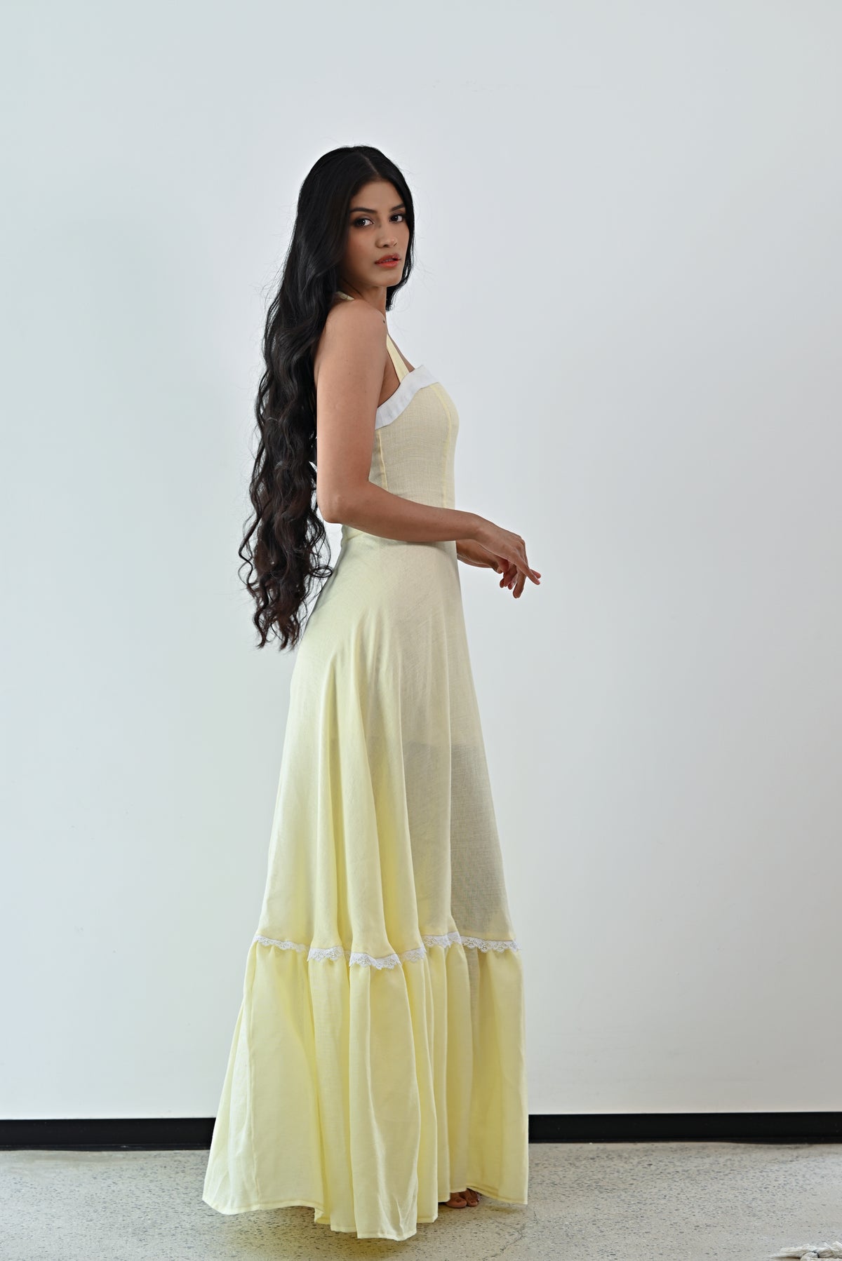 Woman wearing a light yellow dress with a white lace